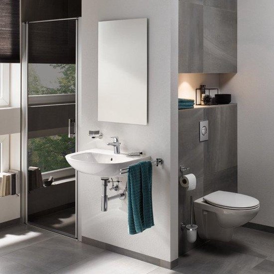 Toiletborstel naast een witte toiletpot in een moderne badkamer.