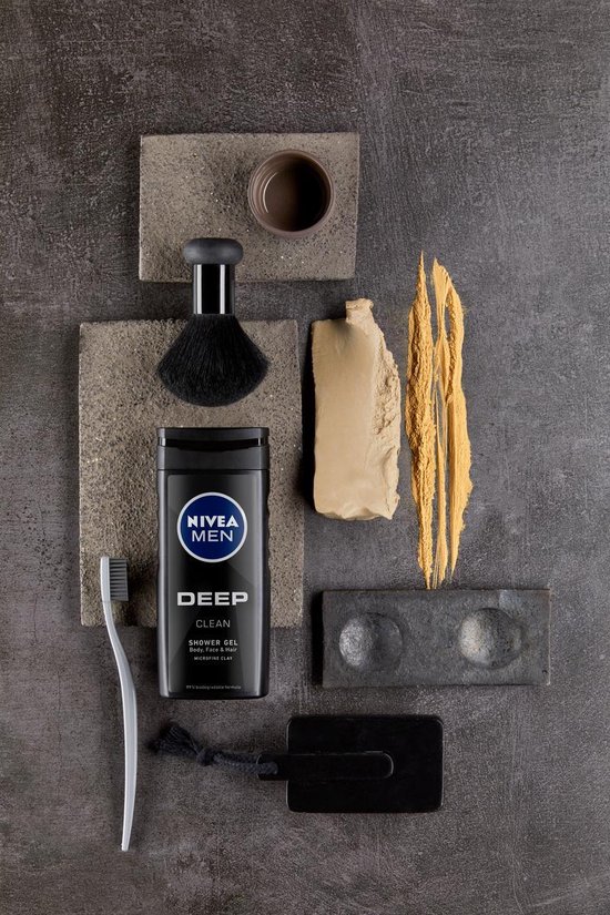 Nivea Men Deep Clean douchegel fles met andere producten: zwarte tandenborstel, scheerkwast, grijze stenen.
