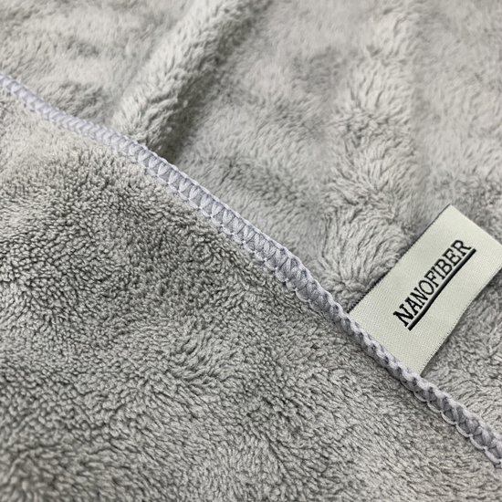 Gedetailleerde close-up van een lichtgrijze, zachte microvezelstof met een 'NANOFIBER' label.