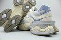 Close-up van de achterkant en zool van twee lichtgrijze New Balance 9060 sneakers met beige en lichtblauwe accenten.