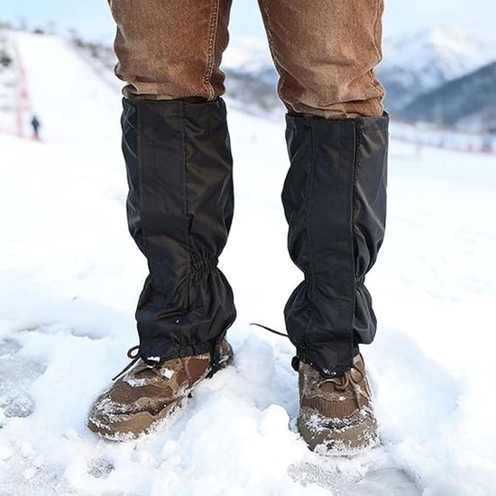 Zwarte, hoge gamaschen over bruine wandelschoenen, op besneeuwd terrein.