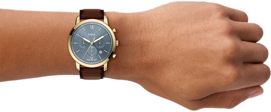 Gouden Fossil horloge met blauwe wijzerplaat en bruine leren band gedragen om een pols.