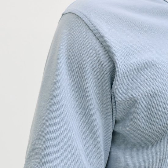 Close-up van de schouder en mouw van een lichtblauw poloshirt.