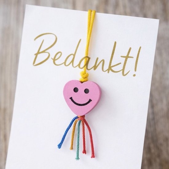 Roze hartjes bedel met lachend gezicht op een kaart met 'Bedankt!'
