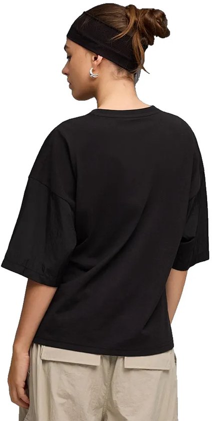 Model draagt de achterkant van een zwarte PUMA oversized T-shirt met korte, wijde mouwen en een hoofdband.