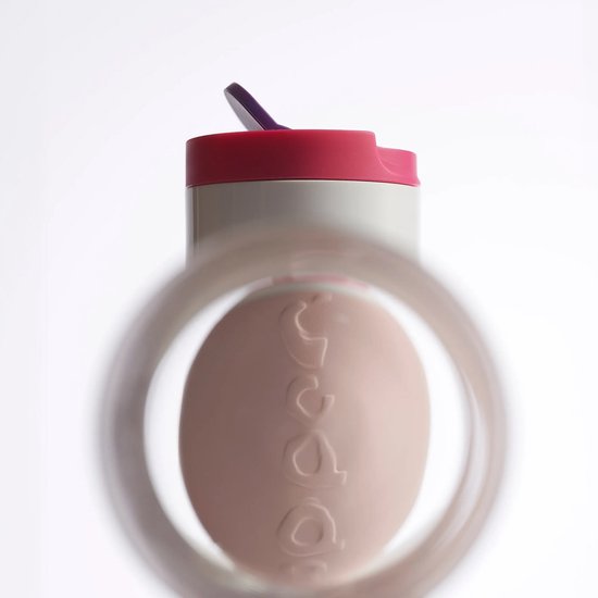 Close-up van de bovenkant van een lichtroze Dopper Travel Mug, gezien door een glas.