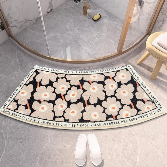 Gebogen badmat in een douchecabine, met een patroon van beige bloemen met oranje middelpunten op een zwarte achtergrond.