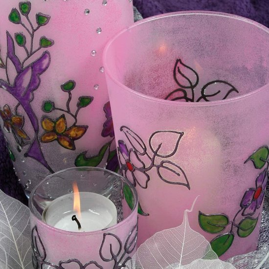 Roze glazen waxinelichthouders met paarse en gele bloemen en gestippelde decoraties.