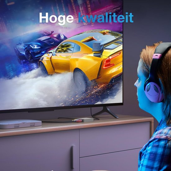 Un jeune avec un casque regarde des voitures de course sur une TV, avec un adaptateur sur la commode.