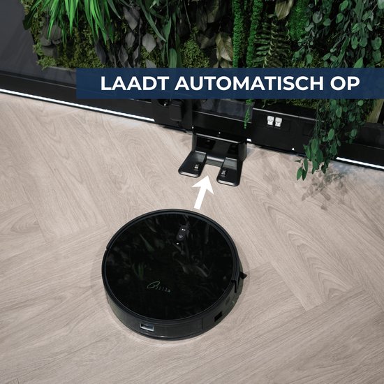 Zwarte robotstofzuiger rijdt naar zwart laadstation bij groene plantenwand.
