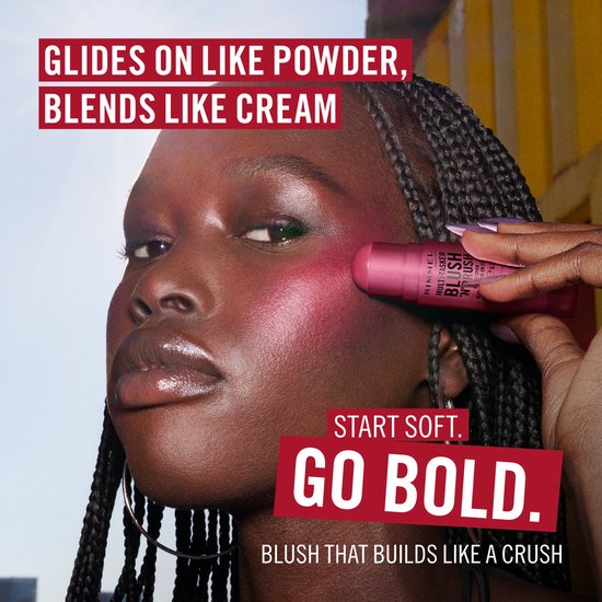 Model met donkere huid met roze blush op de wangen, houdt blush stick vast. Tekst: Glides on like powder, blends like cream.