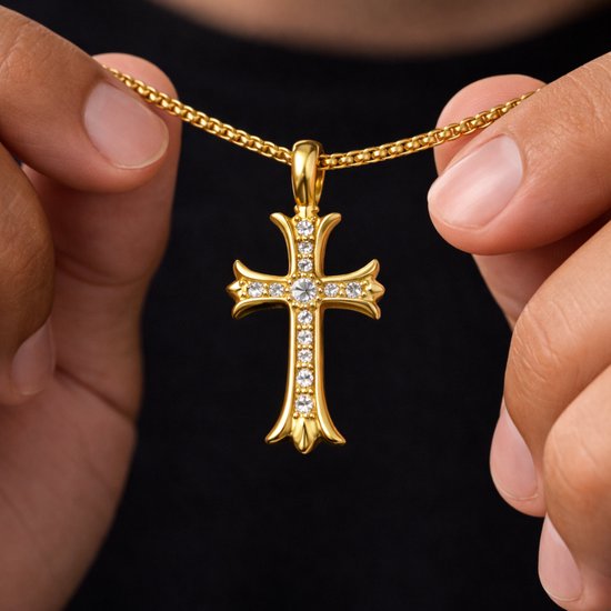 Gouden kruisketting met zirkonia stenen, vastgehouden door handen.