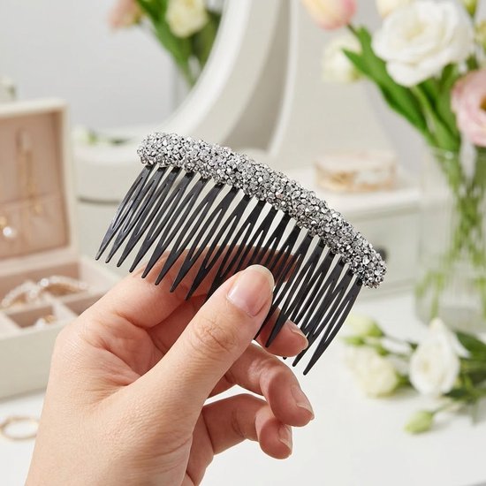 Zilverkleurige haar kam met strass steentjes, vastgehouden in een hand.