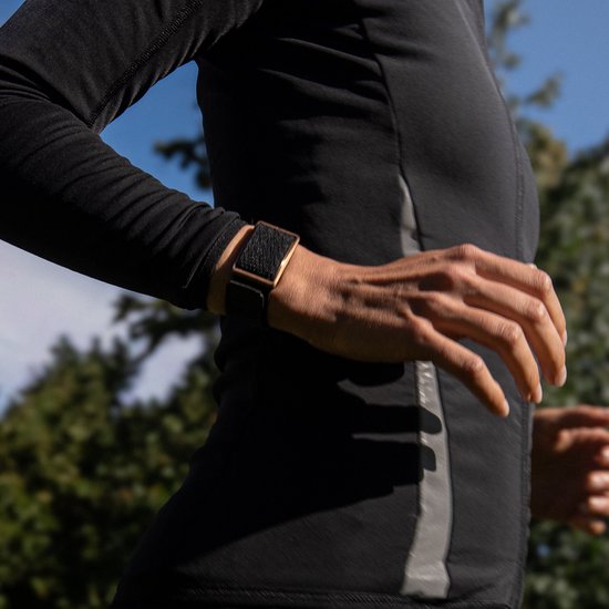 Vrouw rent in de buitenlucht met een zwarte activity tracker om de pols.