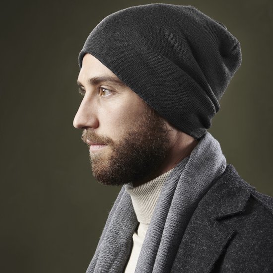 Man met baard draagt een grijze beanie muts, sjaal en coltrui.