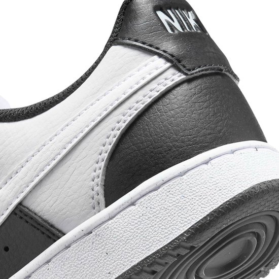 Detail van de hiel van een witte en zwarte Nike sneaker, met het "NIKE" logo op de zwarte hielband.