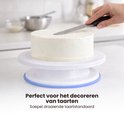 Wit draaiplateau voor taarten met een gladde crème, waarop een taart wordt gedecoreerd.