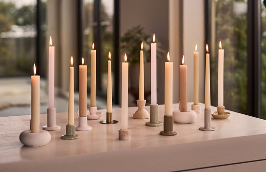 Veelkleurige dinerkaarsen in diverse houders op een tafel.