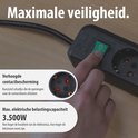 Hand drukt op de groene aan/uit-schakelaar van een zwarte stekkerdoos met verhoogde contactbeveiliging.