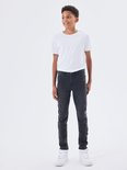 Jongen met witte t-shirt en grijze slim fit spijkerbroek, staand.