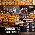 Een winkel met veel kazen, worsten en cadeauboxen. Twee verkopers staan achter de toonbank.