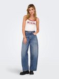 Vrouw in wit crop top met rode bies en wijde, middendonkere spijkerbroek met hoge taille. Zwarte schoenen.