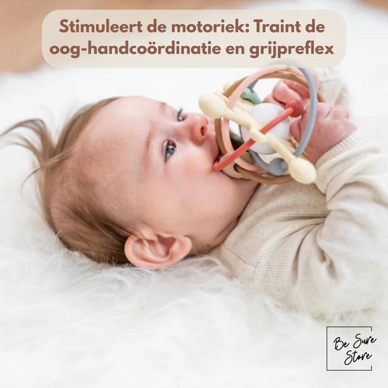 Baby op een witte vacht speelt met de pastelkleurige rammelaar en bijtring.