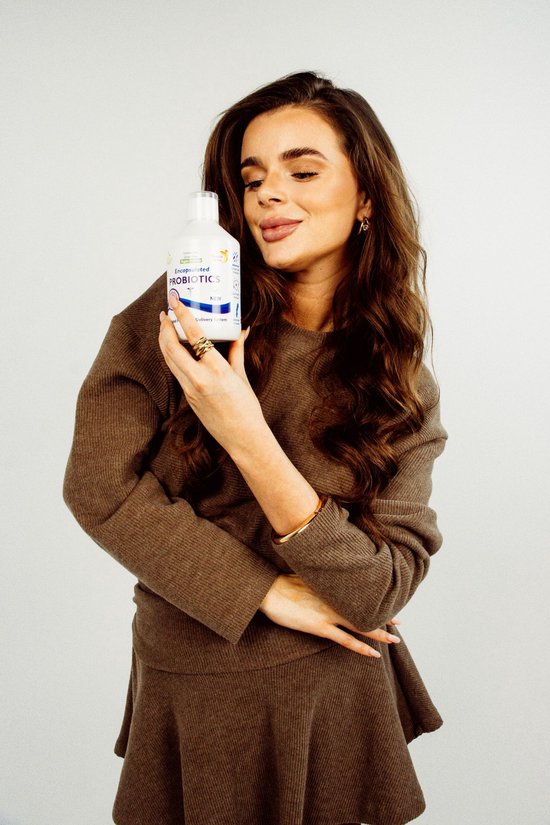 Vrouw met bruin gebreid vest houdt een fles PROBIOTICS omhoog.