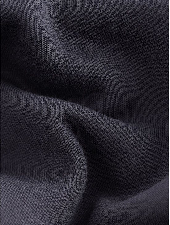 Gedetailleerde close-up van de donkerblauwe gebreide stof van een joggingbroek.