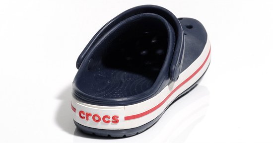 Crocs Crocband bleu marine partiellement visible, avec semelle blanche et rayures rouges. Texte 'Crocs' sur le talon.