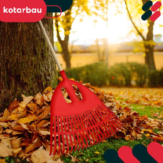 Rode kunststof bladhark naast een boom met herfstbladeren.