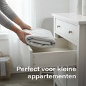 Handen vouwen een grijs gestikt strijkkleed en leggen het in een witte lade.