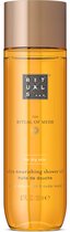 Gouden doucheolie fles met gouden dop. Het etiket is oranje met tekst in het wit en goud.