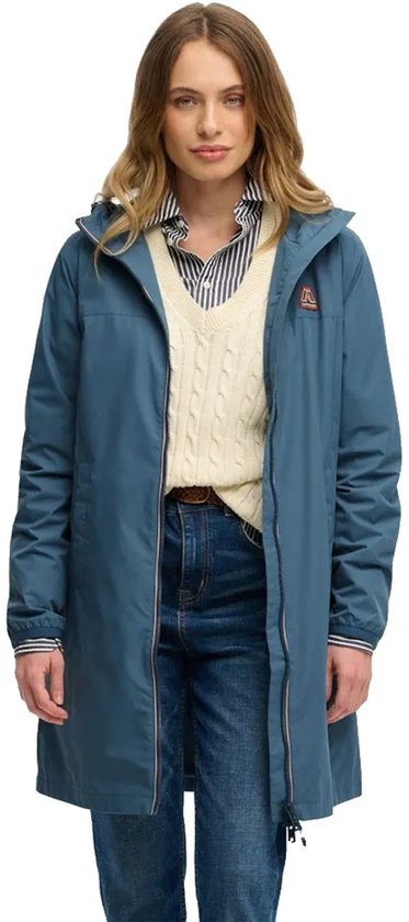 Vrouw in lange blauwe windjack, gestreepte blouse, gebreide trui en jeans