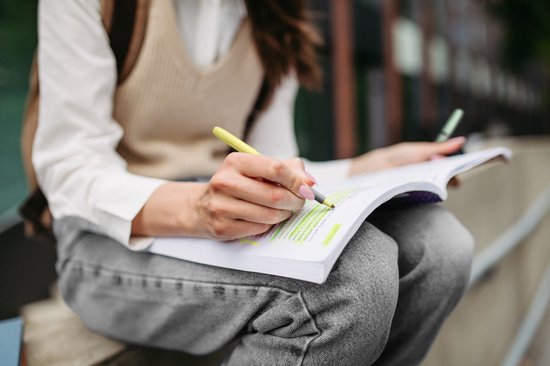 Persoon markeert een boek met een pastelgele BIC Highlighter Grip marker.