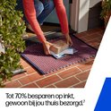 Een vrouw met oranje trui legt een pakketje met HP Instant Ink en brieven op een deurmat.