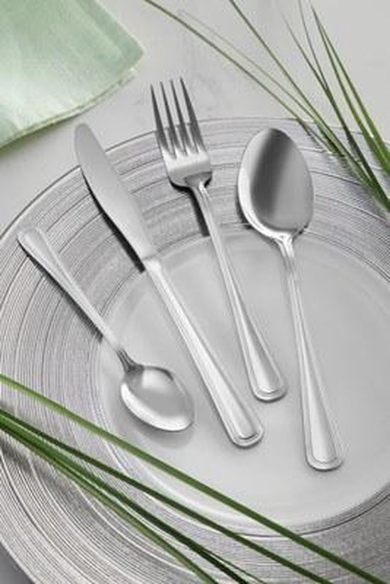 Un couteau, une fourchette et deux cuillères sur une assiette, décorés d'une serviette verte et de plantes.