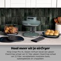 Grijze Ninja airfryer op aanrecht met 2 glazen schalen met eten. Eén met kip en groenten, één met broodjes. Tekst: Haal meer uit je airfryer.