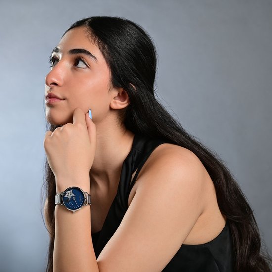 Jongedame met lang zwart haar, draagt een zilverkleurig horloge met donkerblauwe wijzerplaat en sterren.