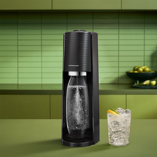 Zwarte Sodastream bruiswatermaker met een glas bruisend water op een groen aanrecht.