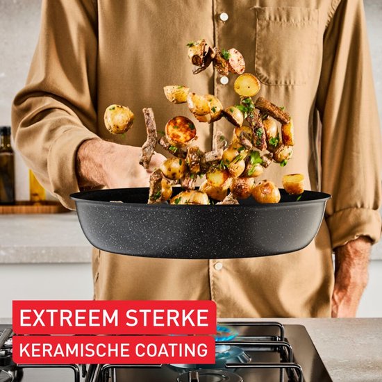 Een man gooit eten, aardappelen en vlees, uit een diepe pan. EXTREEM STERKE KERAMISCHE COATING staat in een rode balk.
