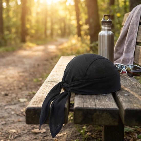 Zwarte mesh bandana met lange linten op een houten bankje in een bos.