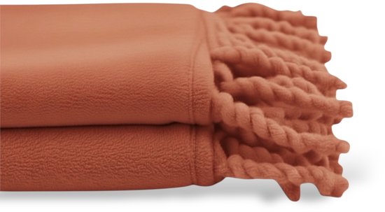Plaid polaire orange plié avec de épaisses franges torsadées.