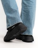 Dames met blauwe jeans dragen zwarte Steve Madden sneakers.