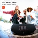 Enceinte JBL noire avec lettrage rouge sur fond de pierre, trois femmes dansent.