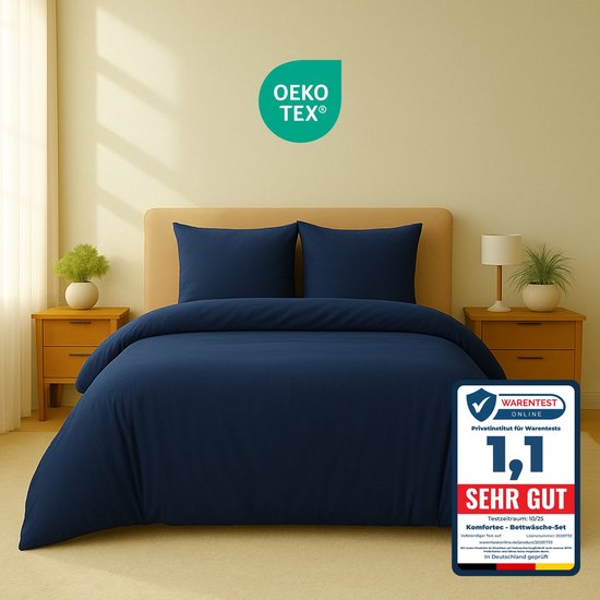Een opgemaakt donkerblauw bed met een dekbedovertrek en twee kussenslopen. Een 'OEKO-TEX' logo en een 'Warentest' keurmerk zijn zichtbaar.