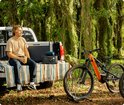 Donkergrijs Jackery Explorer 500 powerstation met oranje accenten, op de laadbak van een pick-up truck, naast een mountainbike.