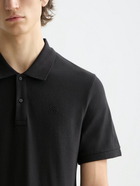 Detail van een zwarte poloshirt met korte mouwen en een geborduurd logo.