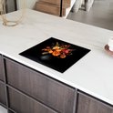 Zwarte inductiebeschermer met een boeket bloemen in herfstkleuren, op een wit marmeren aanrecht.