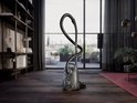 Zwarte AEG stofzuiger in een moderne woonkamer met open haard, plank en uitzicht op de stad.
